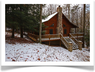 tall tree next to snow covered cabin with stairs to wrap around porch