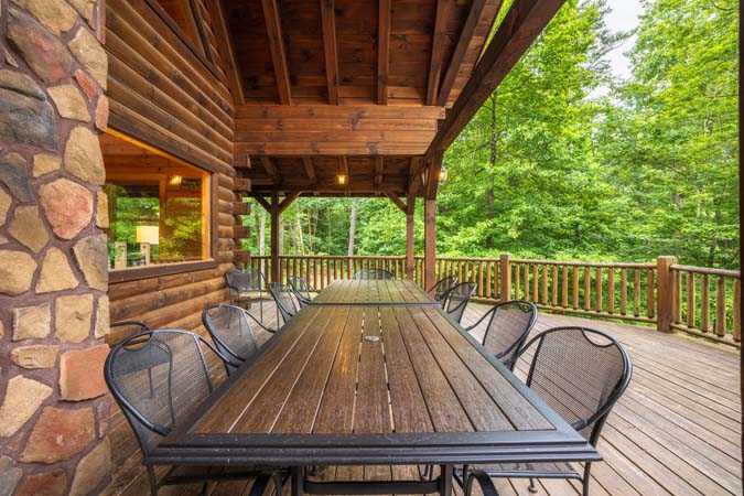 Covered deck dining with a forest view — Timber Ridge Lodge